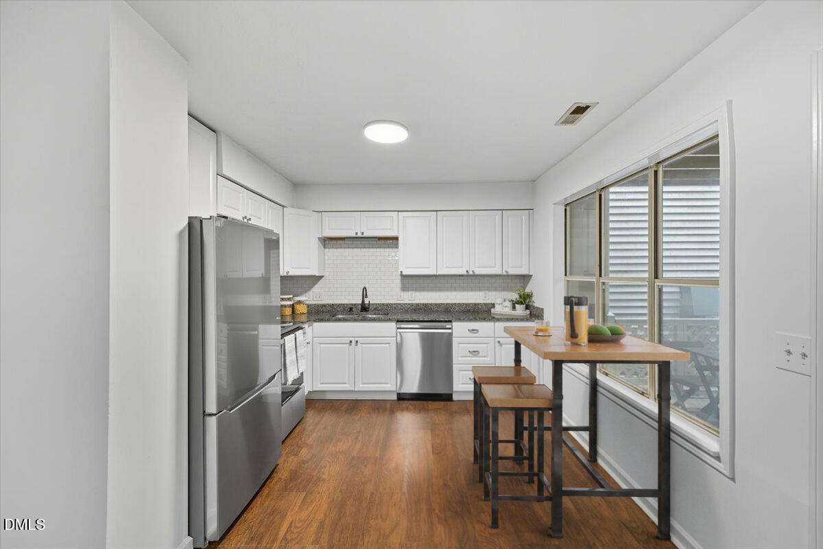 102 Choptank Court, Unit A2 Cary, NC 27513 - Photo 7 of 24 a kitchen with stainless steel appliances a refrigerator a sink dishwasher a stove and white cabinets with wooden floor