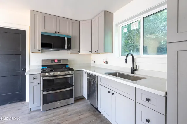 a kitchen with cabinets stainless steel appliances a sink and a window