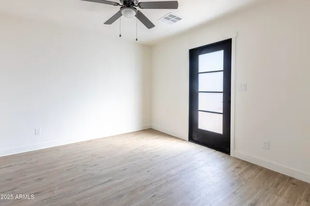 an empty room with wooden floor closet and windows