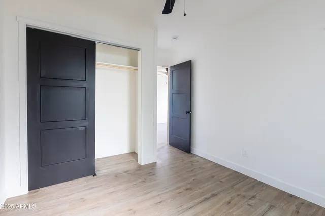 a view of an empty room with wooden floor and closet