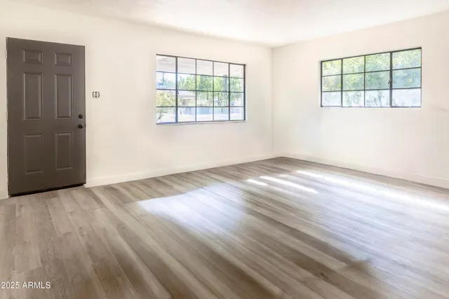 an empty room with wooden floor and windows