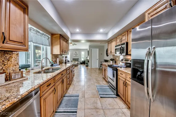a kitchen with granite countertop a sink a window and cabinets