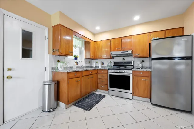 a kitchen with granite countertop a refrigerator stove top oven and sink