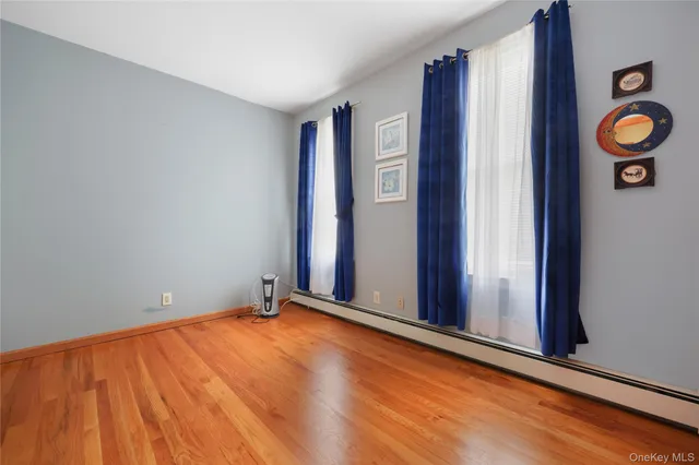 a view of an empty room with wooden floor and window