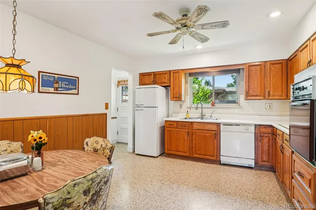 a kitchen with stainless steel appliances granite countertop a refrigerator a sink dishwasher a stove a dining table and chairs with wooden floor