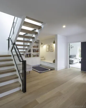 a view of an empty room with wooden floor and stairs