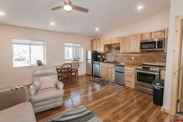 a living room with stainless steel appliances furniture and a kitchen view