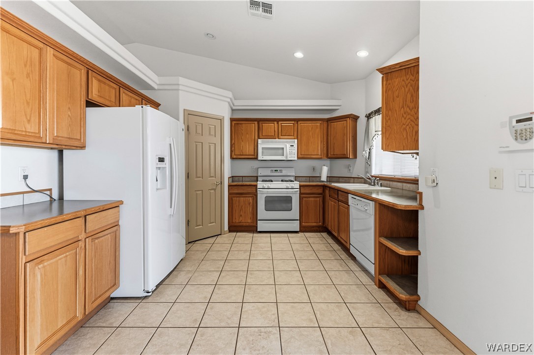 3973 Prairie View Drive Kingman, AZ 86409 - Photo 15 of 34 The kitchen features tile flooring, wood cabinetry, a white refrigerator, a white range, and a white dishwasher