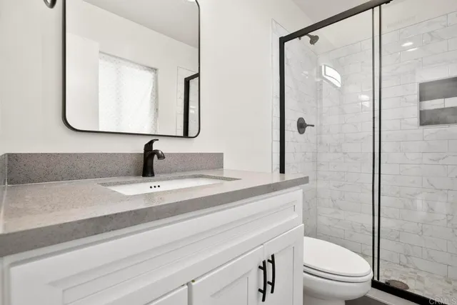 a bathroom with a granite countertop sink toilet a mirror and shower