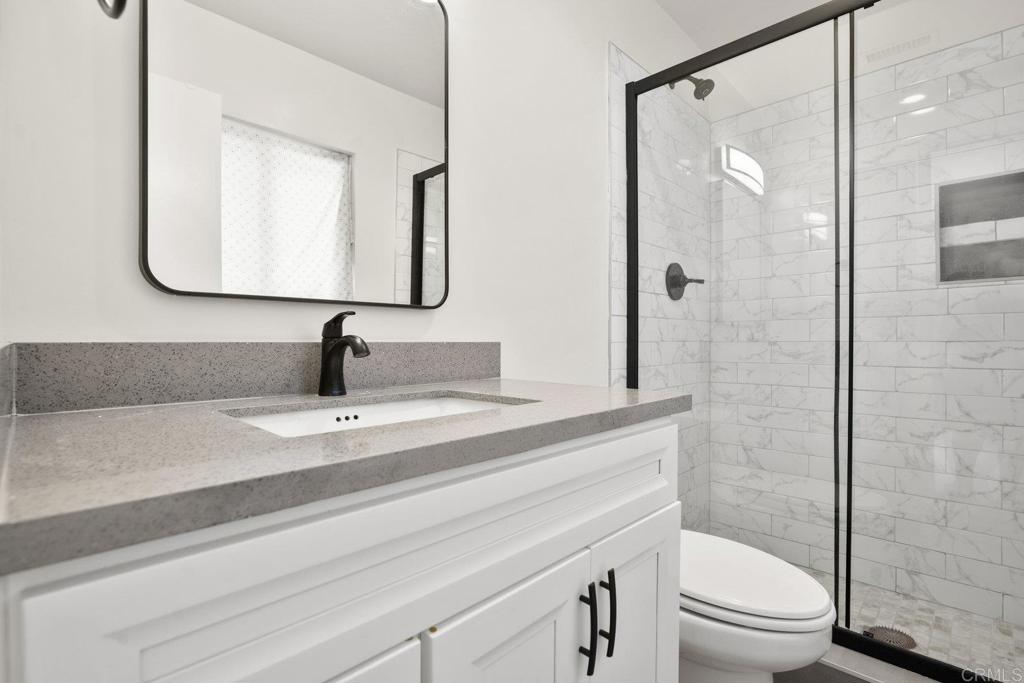 809 Buchanan Street Escondido, CA 92027 - Photo 20 of 32 a bathroom with a granite countertop sink toilet a mirror and shower