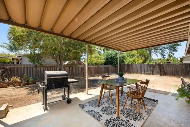 a view of a patio with table and chairs and couches with wooden fence and plants