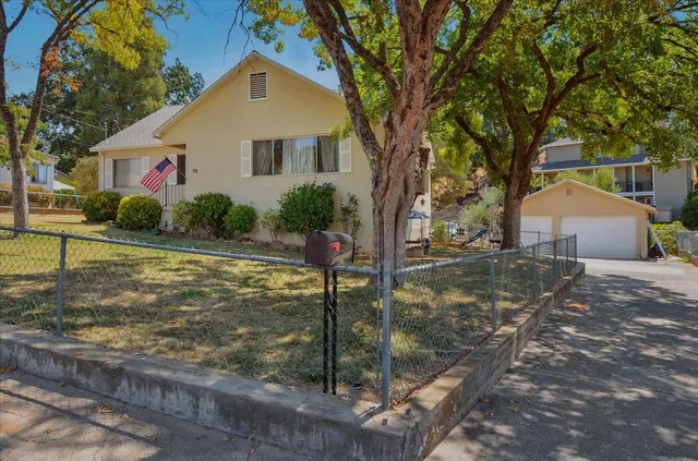 a front view of house with yard and trees in the background