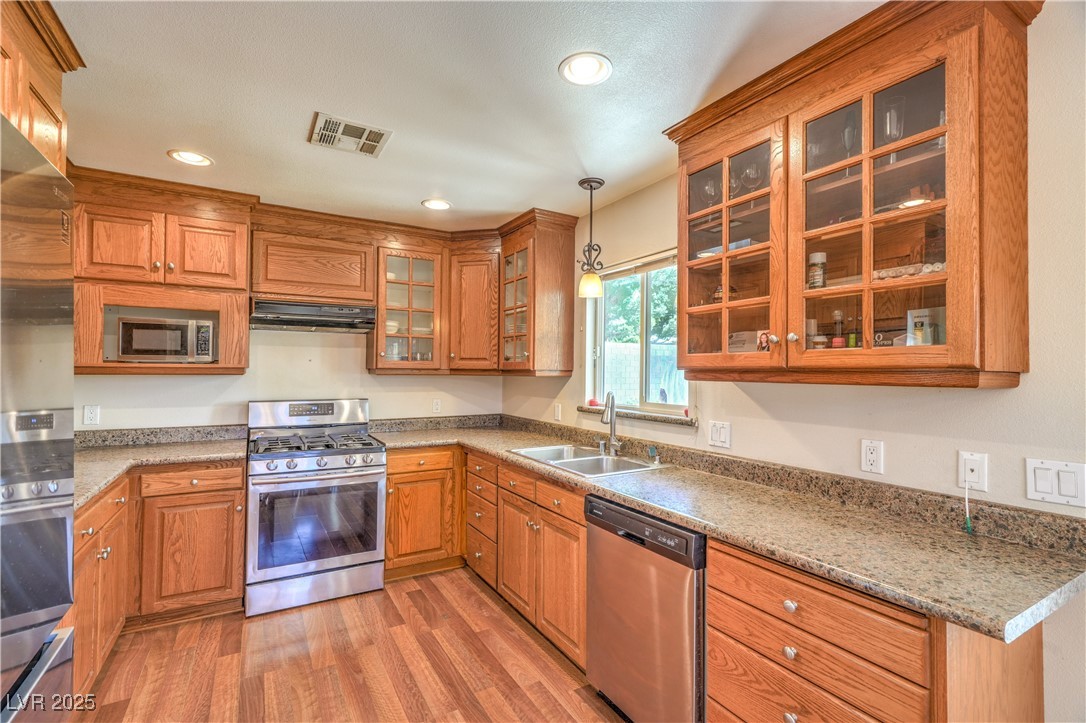 1201 I Boulder City, NV 89005 - Photo 11 of 26 Kitchen with stainless steel appliances, brown cabinets, light wood-type flooring, hanging light fixtures, and recessed lighting