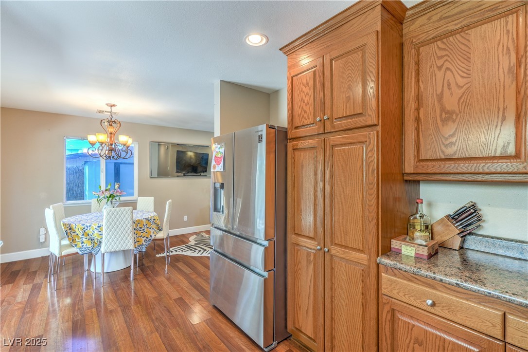 1201 I Boulder City, NV 89005 - Photo 13 of 26 Kitchen featuring stainless steel fridge, brown cabinets, a chandelier, dark wood-type flooring, and pendant lighting
