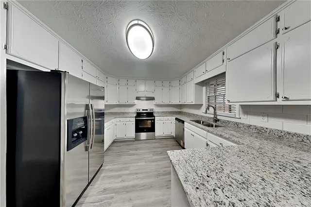 a large kitchen with stainless steel appliances granite countertop a stove a sink and a refrigerator
