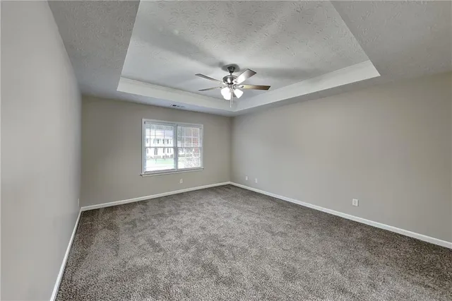an empty room with windows and ceiling fan
