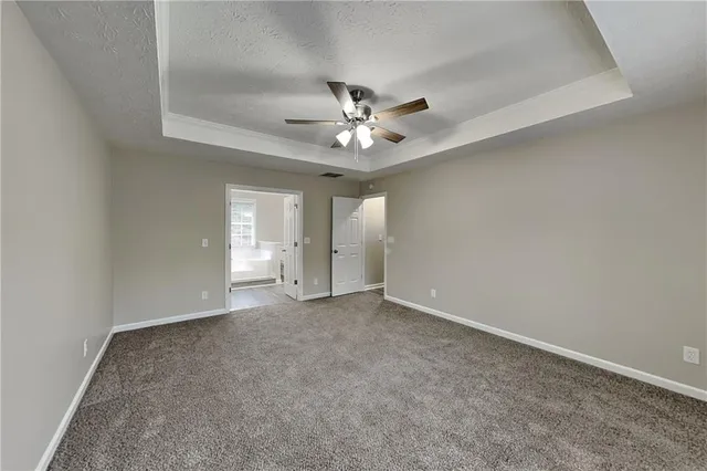 an empty room with chandelier fan and windows