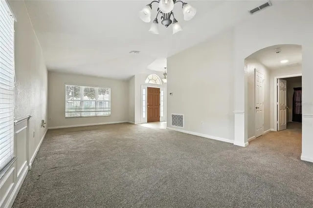 a view of a big room with windows and chandelier fan