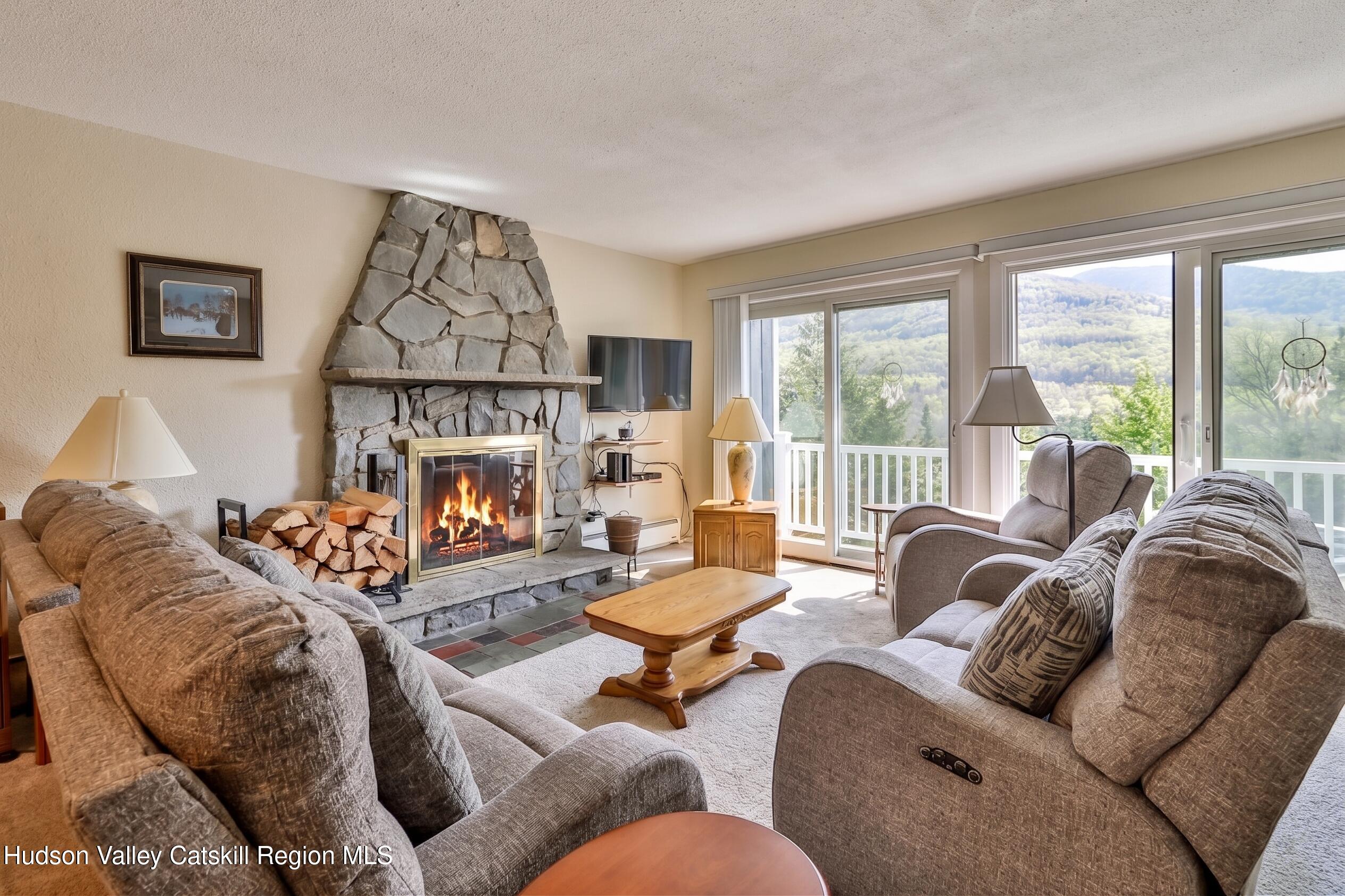 33 Scribner Hollow Road, Unit E4 Hunter, NY 12442 - Photo 6 of 44 a living room with furniture a fireplace and a large window
