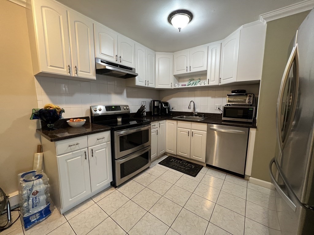 1 Universal Street, Unit 7 Framingham, MA 01702 - Photo 4 of 23 a kitchen with a sink dishwasher stove and white cabinets