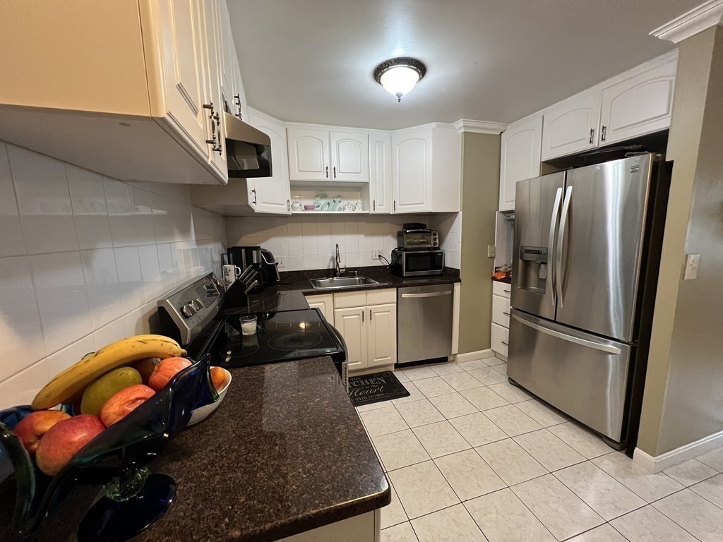 1 Universal Street, Unit 7 Framingham, MA 01702 - Photo 7 of 23 a kitchen with stainless steel appliances granite countertop a sink a stove a refrigerator and cabinets