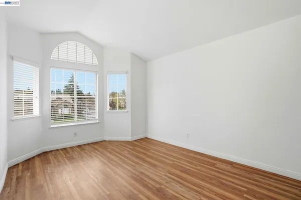 an empty room with wooden floor exposed radiator and windows