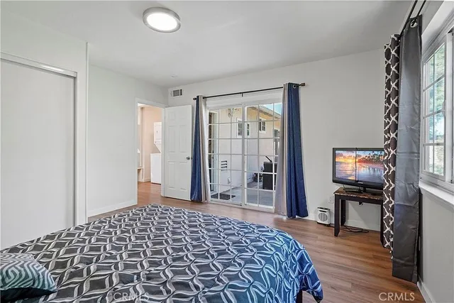 a bedroom with a bed and a flat tv screen next to a window