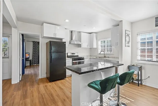 a kitchen with stainless steel appliances granite countertop a refrigerator a sink a stove a dining table and chairs