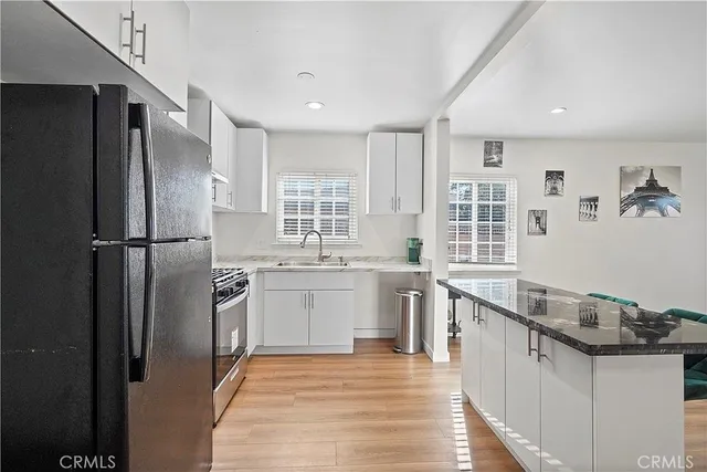 a kitchen with stainless steel appliances granite countertop a refrigerator a sink and a stove