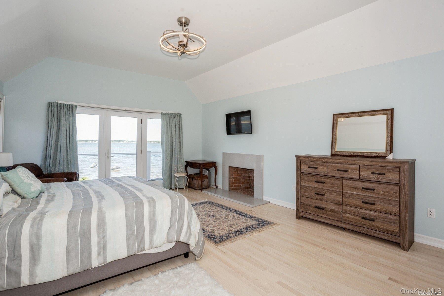 676 Dune Road West Hampton Dunes, NY 11978 - Photo 11 of 20 a spacious bedroom with a bed a fireplace and a flat tv screen