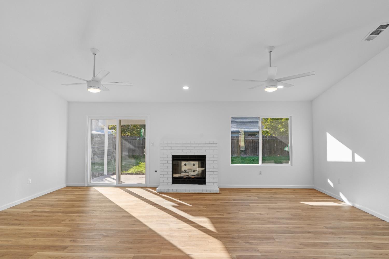 1509 Boothe Road Ceres, CA 95307 - Photo 10 of 28 an empty room with a fireplace and windows