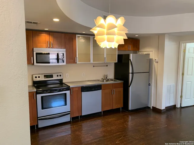 a kitchen with stainless steel appliances granite countertop a refrigerator a stove a sink dishwasher and a refrigerator with wooden floor