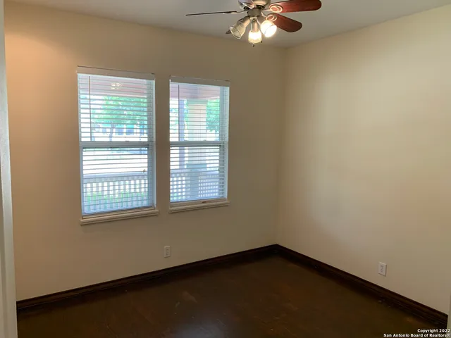 an empty room with wooden floor chandelier and windows