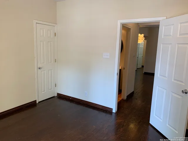 an empty room with wooden floor and windows with curtains