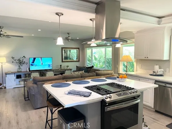 a kitchen with a stove a sink a dining table and chairs with wooden floor