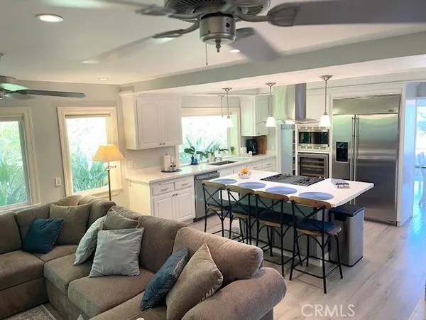 a living room with stainless steel appliances kitchen island furniture and a large window
