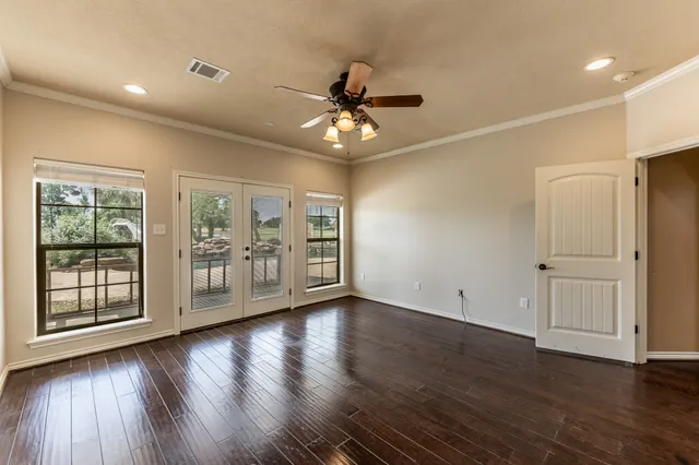 a view of an empty room with a window and wooden floor