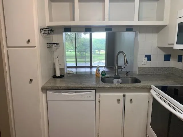 a kitchen with stainless steel appliances granite countertop a sink and a refrigerator