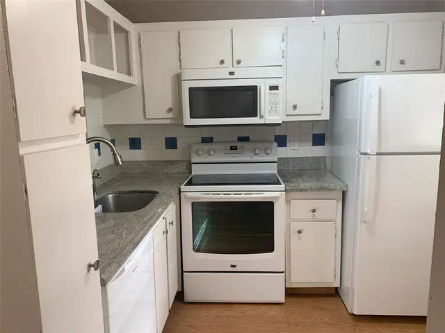 a kitchen with white cabinets and white appliances