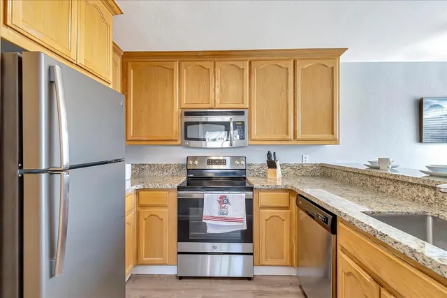 a kitchen with stainless steel appliances granite countertop a stove a refrigerator and a sink