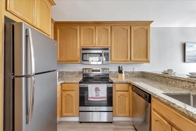 a kitchen with stainless steel appliances granite countertop a stove a refrigerator and a sink