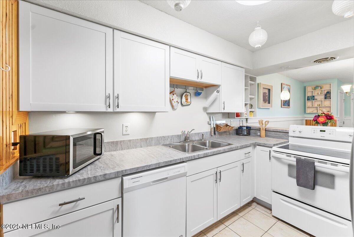 125 Rio Del Mar Street, Unit A St. Augustine, FL 32080 - Photo 6 of 30 a kitchen with granite countertop white cabinets and white appliances