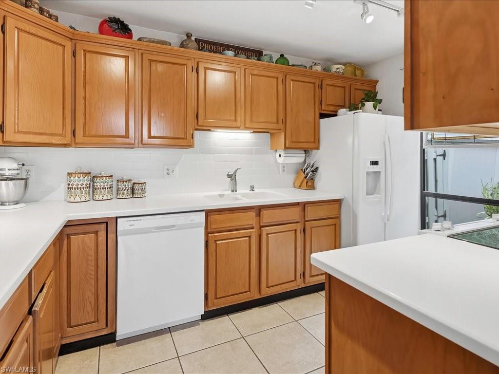 1337 Solana Road Naples, FL 34103 - Photo 8 of 23 Kitchen featuring light wood cabinetry, white countertops, white subway tile backsplash, a double basin sink with a chrome faucet, and tile flooring