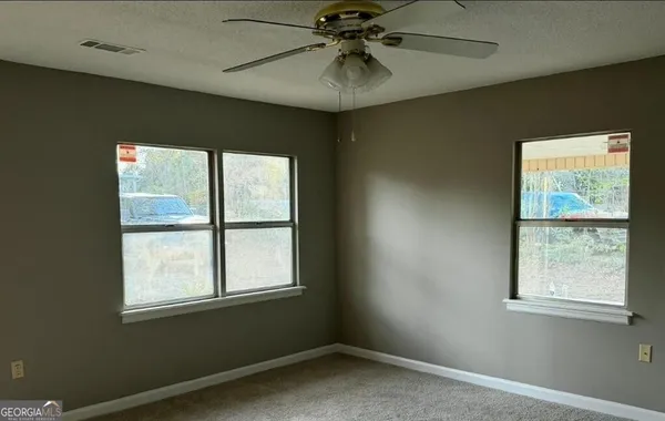 a view of empty room with window and chandelier fan