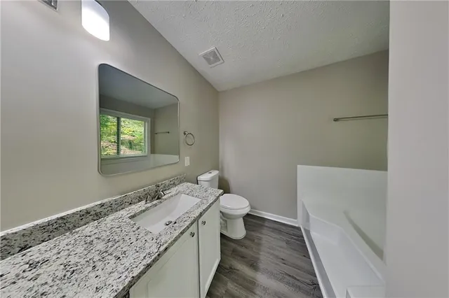 a bathroom with a granite countertop sink mirror vanity and toilet