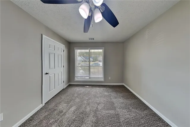 an empty room with chandelier fan and windows