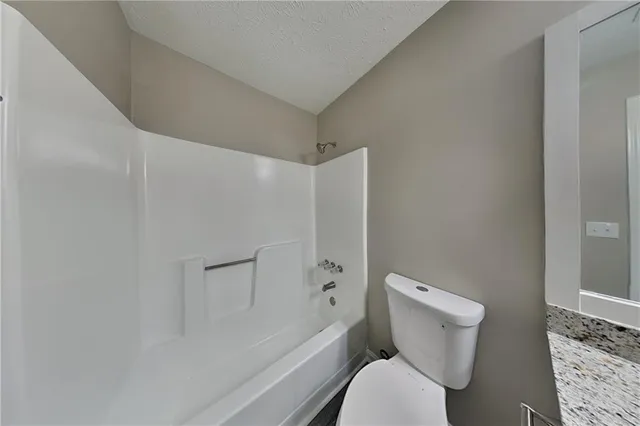 a white toilet sitting next to a bath tub