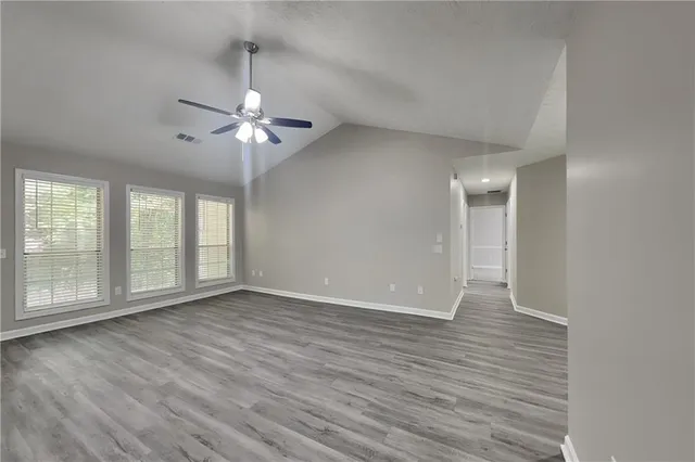 a view of an empty room with a window and wooden floor