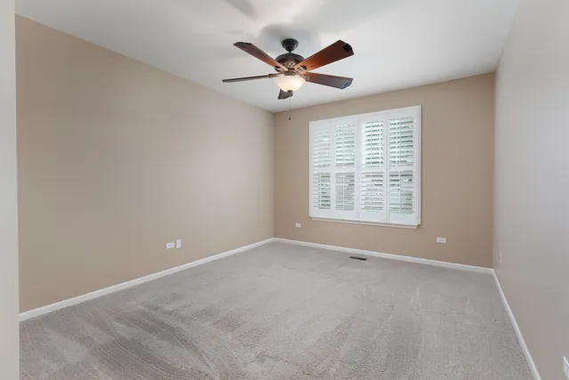 a view of an empty room with a ceiling fan and window