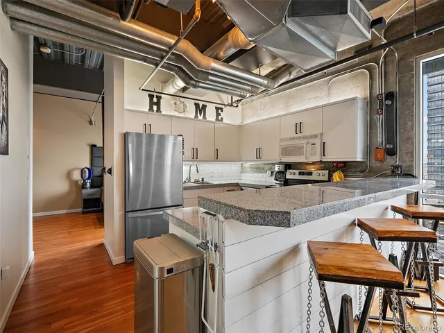 a kitchen with granite countertop a refrigerator and a stove top oven